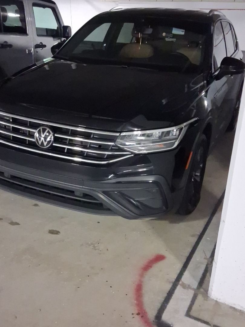 Black Volkswagen SUV parked in a garage, front view with headlights and grille visible