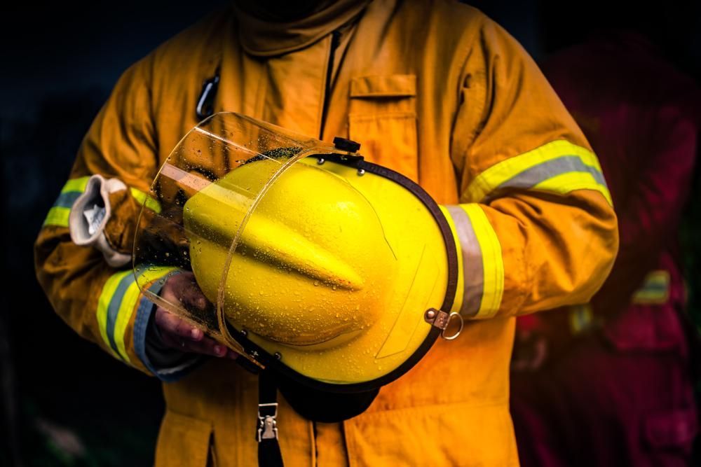 A Fireman in A Yellow Suit Is Holding a Yellow Helmet — Stellar Test and Tag in Narrabri, NSW