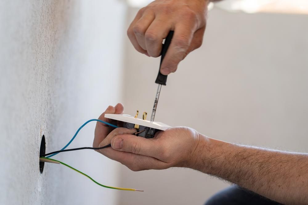 A Man Is Fixing an Electrical Outlet with A Screwdriver — Stellar Test and Tag in Tamworth, NSW