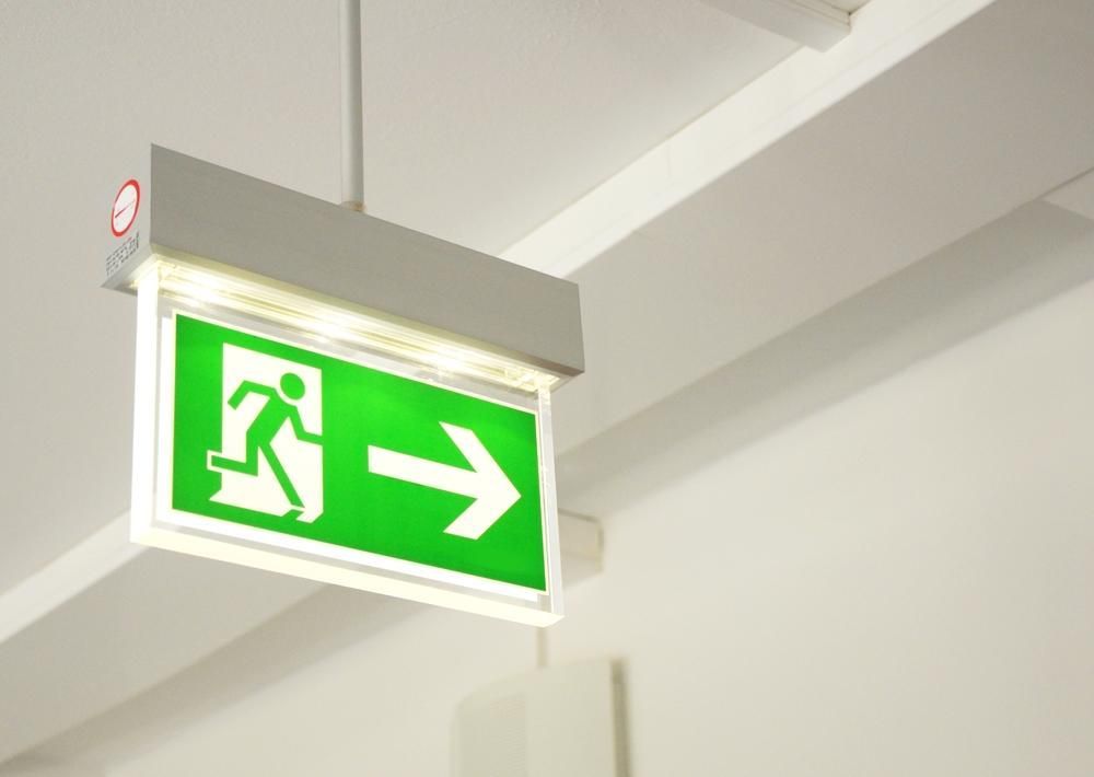 A Green Exit Sign Is Hanging from The Ceiling of A Building — Stellar Test and Tag in Armidale, NSW