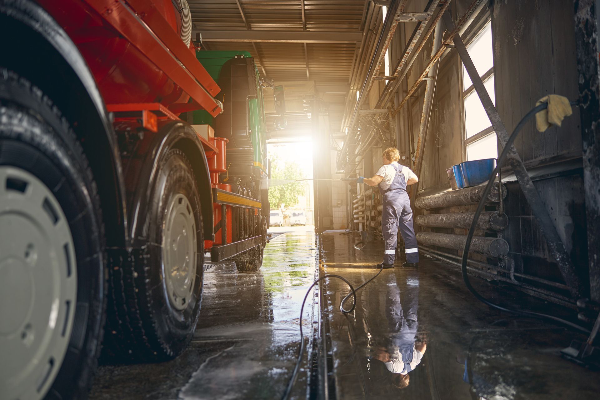 A man is washing a truck in a garage.
