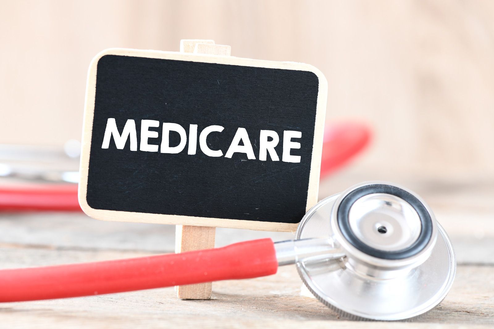 A sign that says medicare next to a stethoscope on a wooden table.