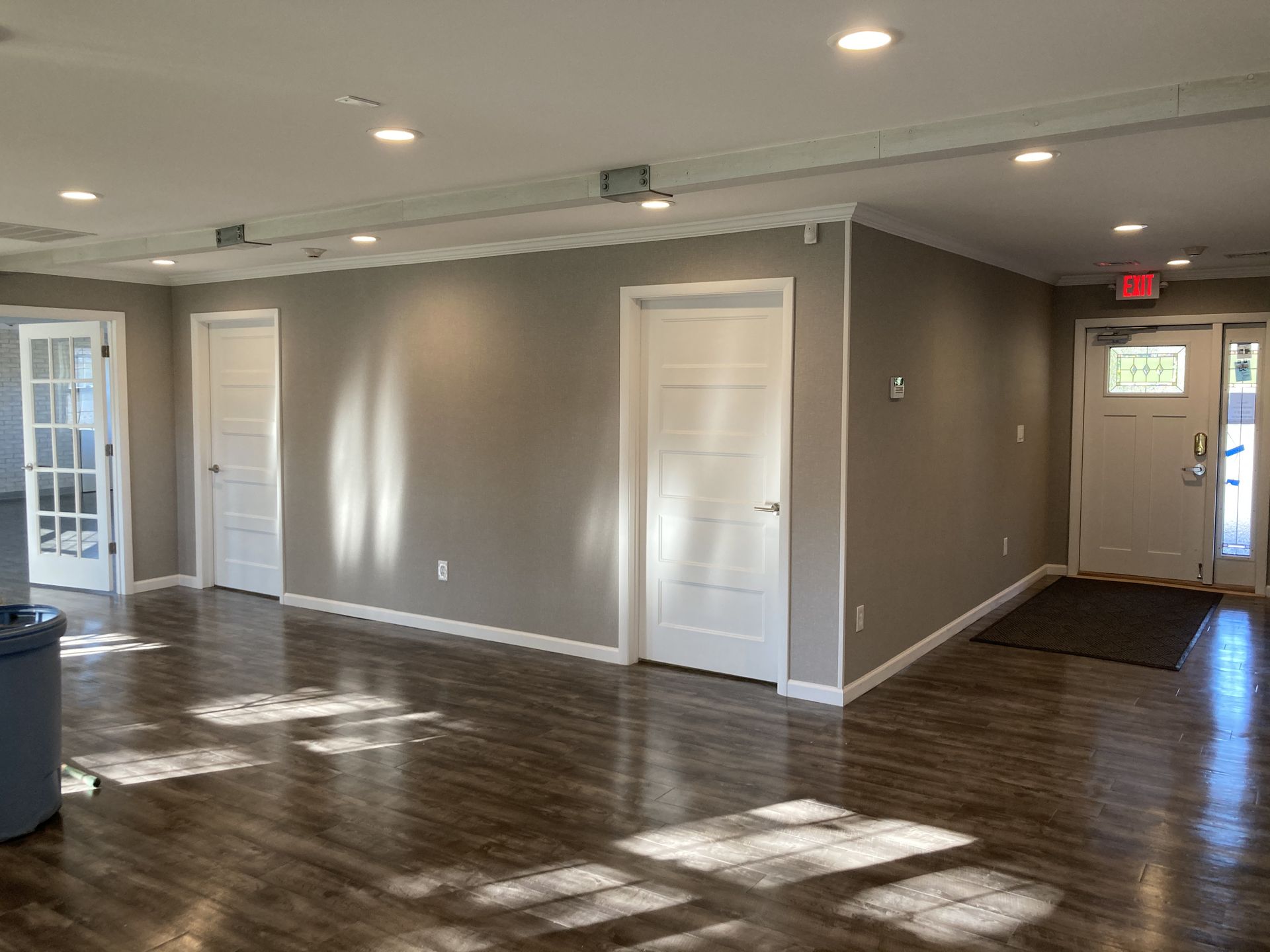 an empty room with a white door and a red exit sign