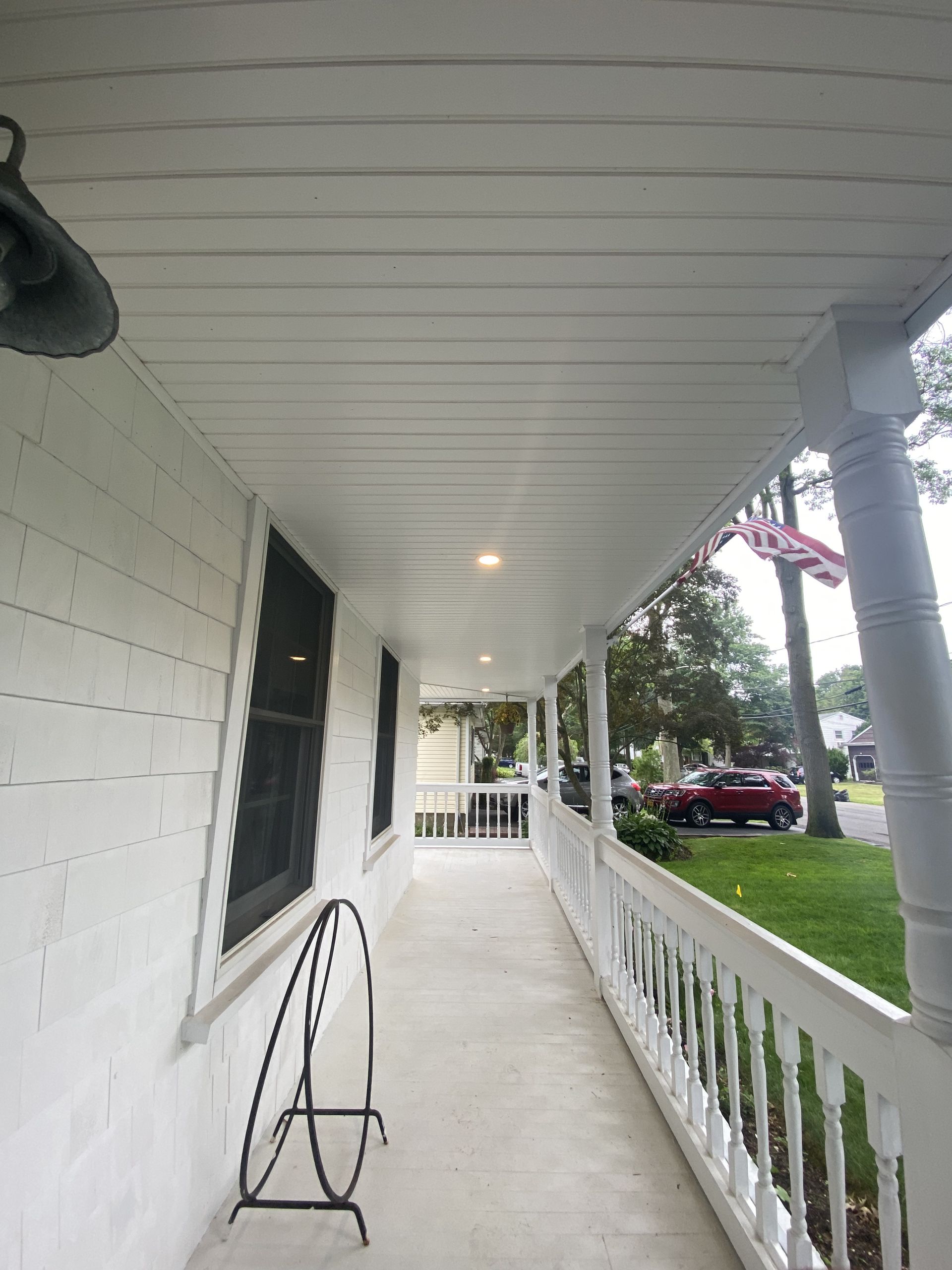 a white porch with a red car parked on the side