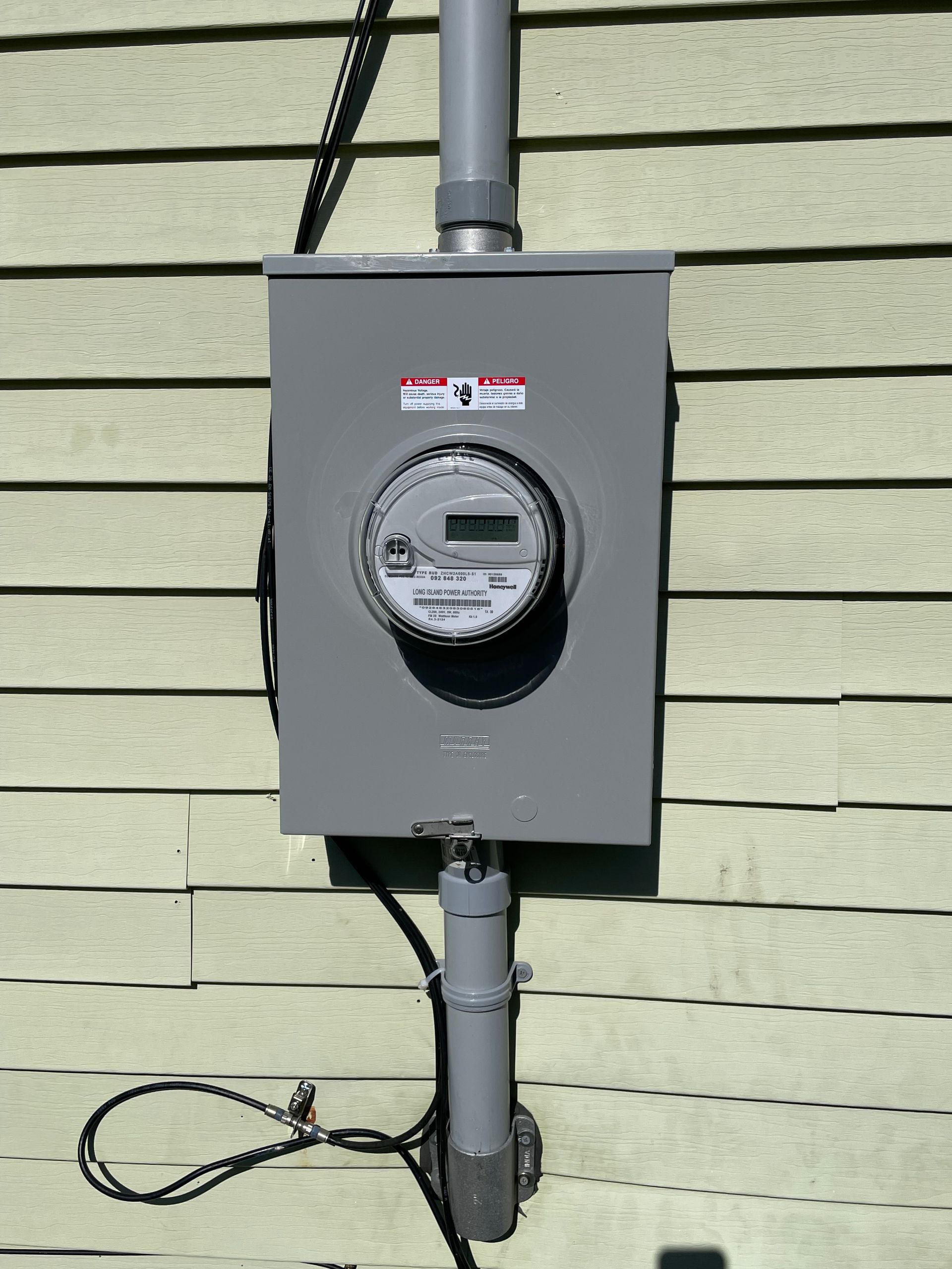 a meter on the side of a house has a warning label on it