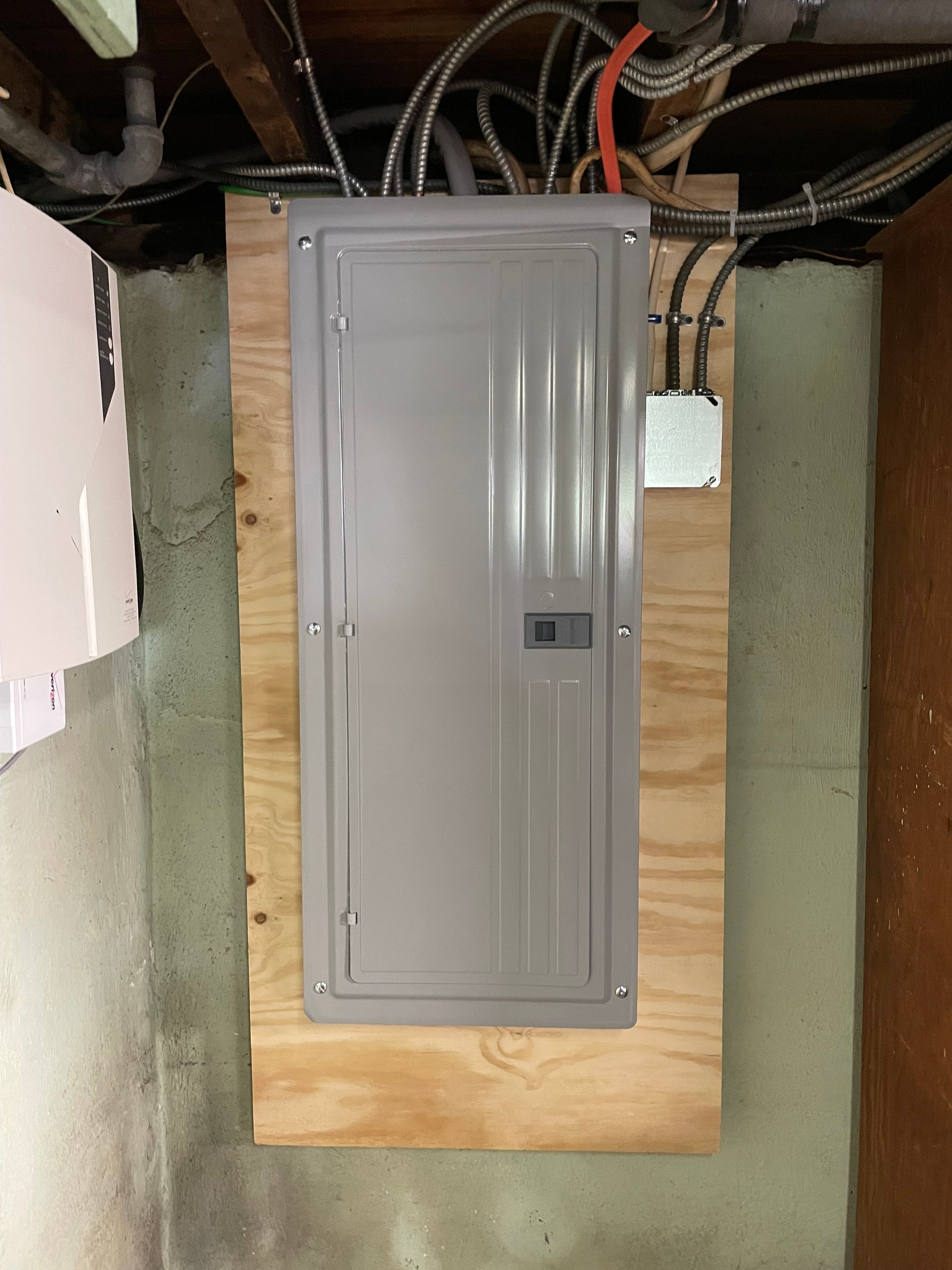 a gray electrical box is mounted on a wooden board