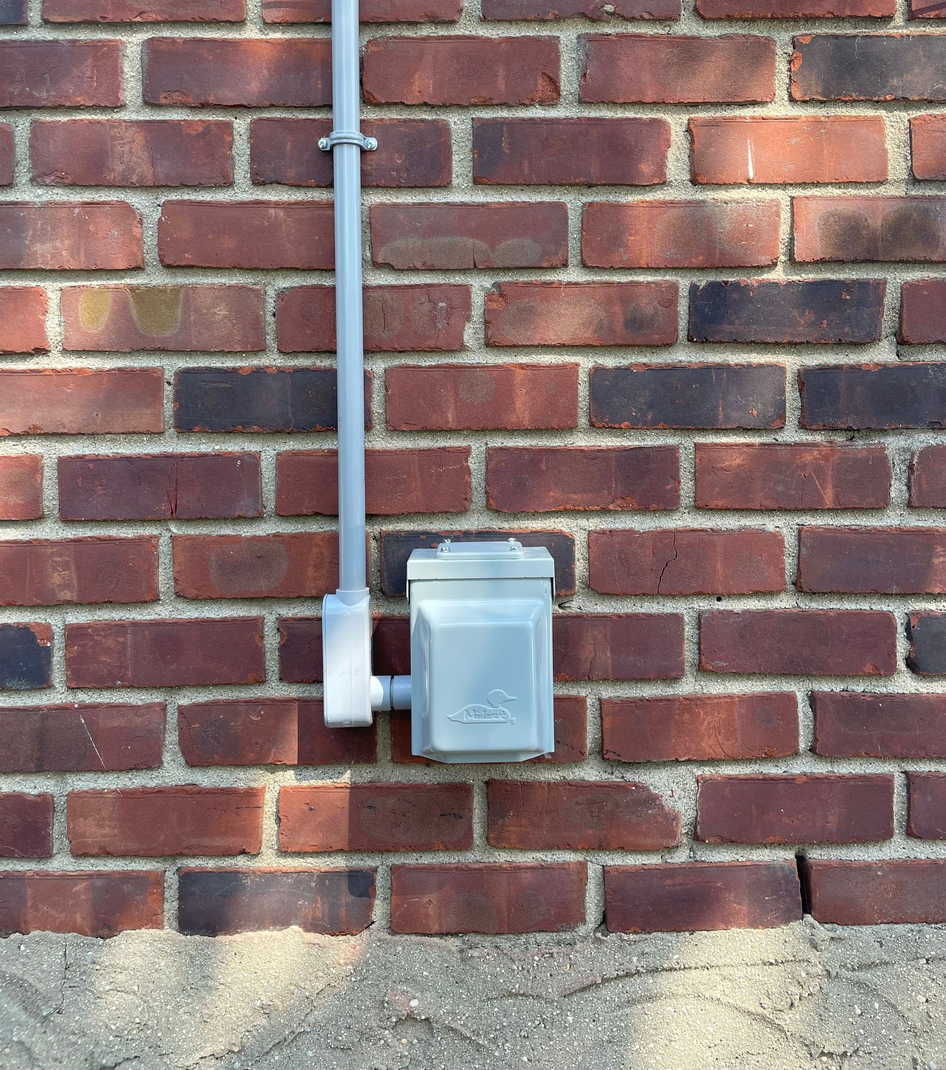 a brick wall with a gray electrical box on it