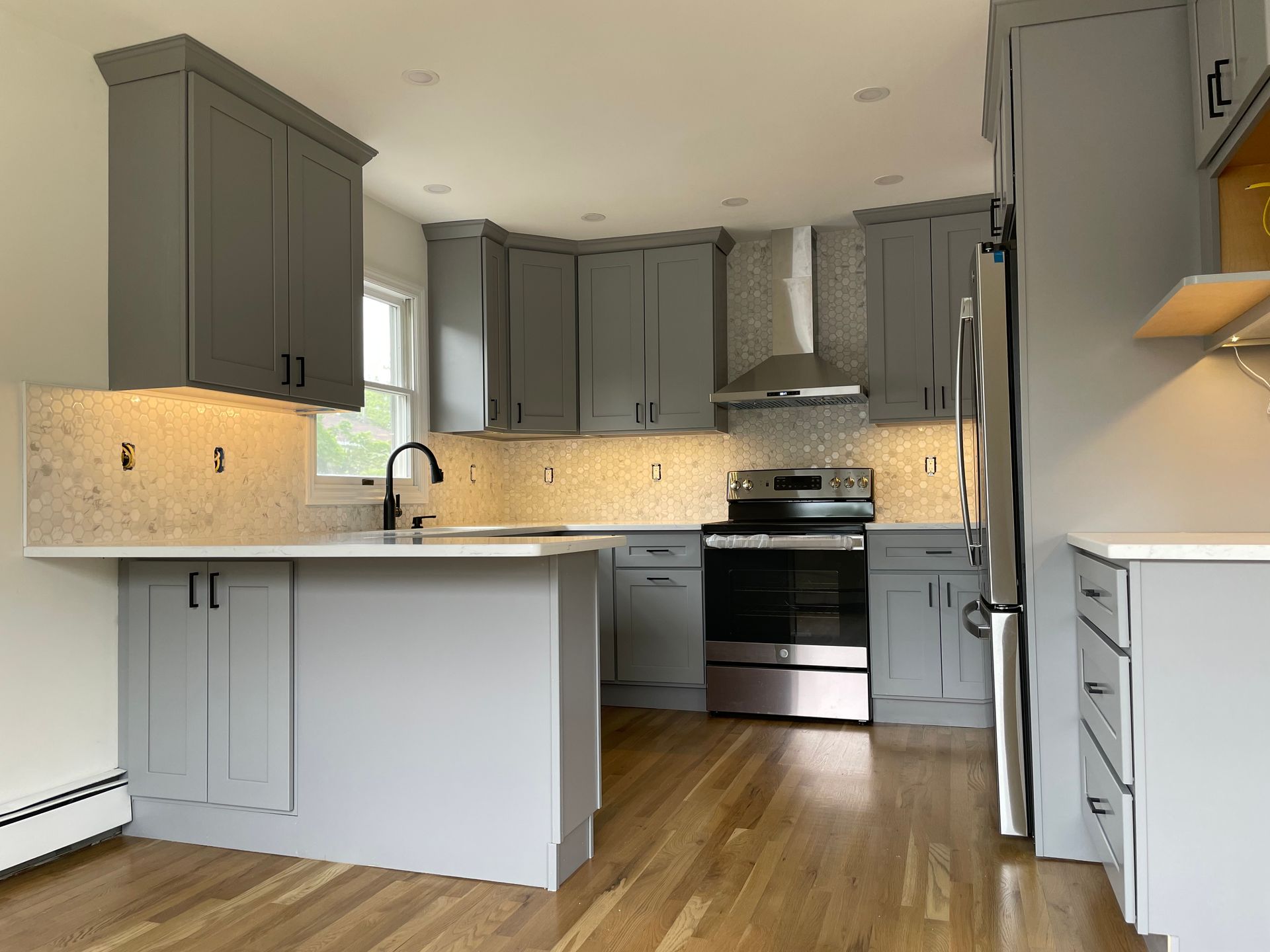 a kitchen with gray cabinets and stainless steel appliances