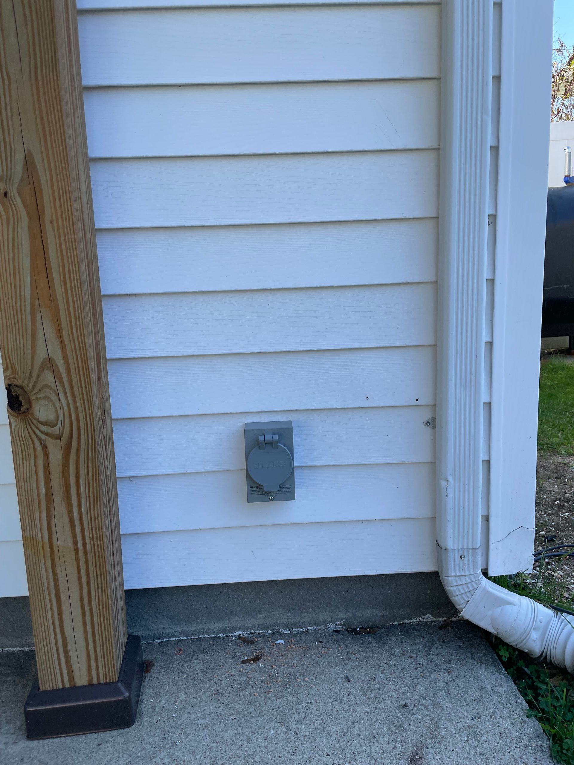 a white house has a gray electrical outlet on the side