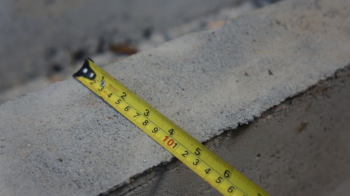 A yellow tape measure is laying on a concrete surface.