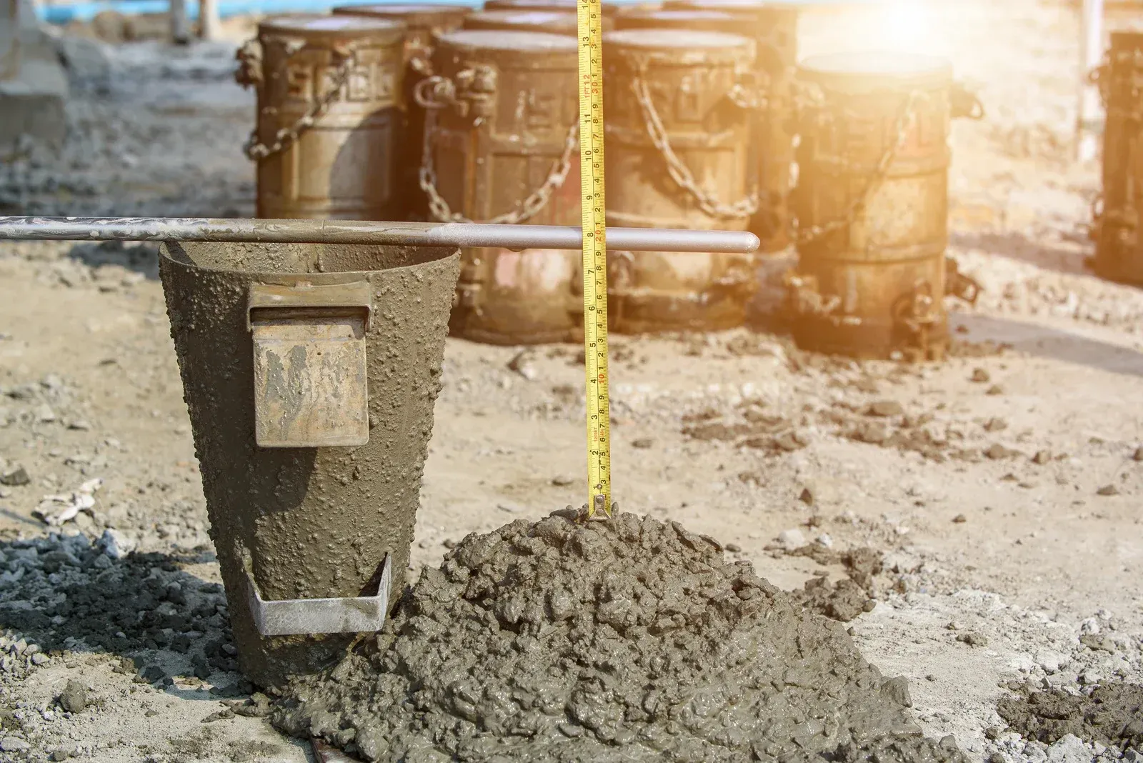 A bucket of concrete is being measured with a tape measure.