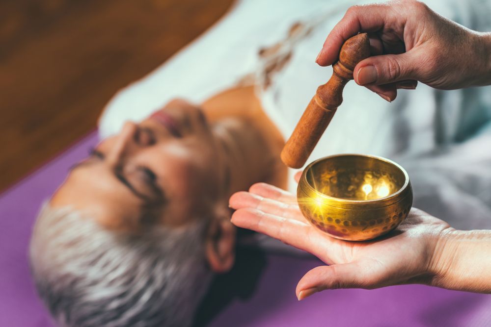 A Woman is Laying While a Person Holds a Singing Bowl in Their Hand — Angel of Light Nick Turner In East Lismore, NSW