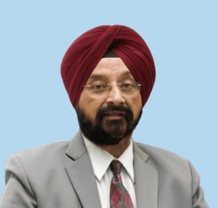 Man with maroon turban and beard, wearing a suit, looking forward.