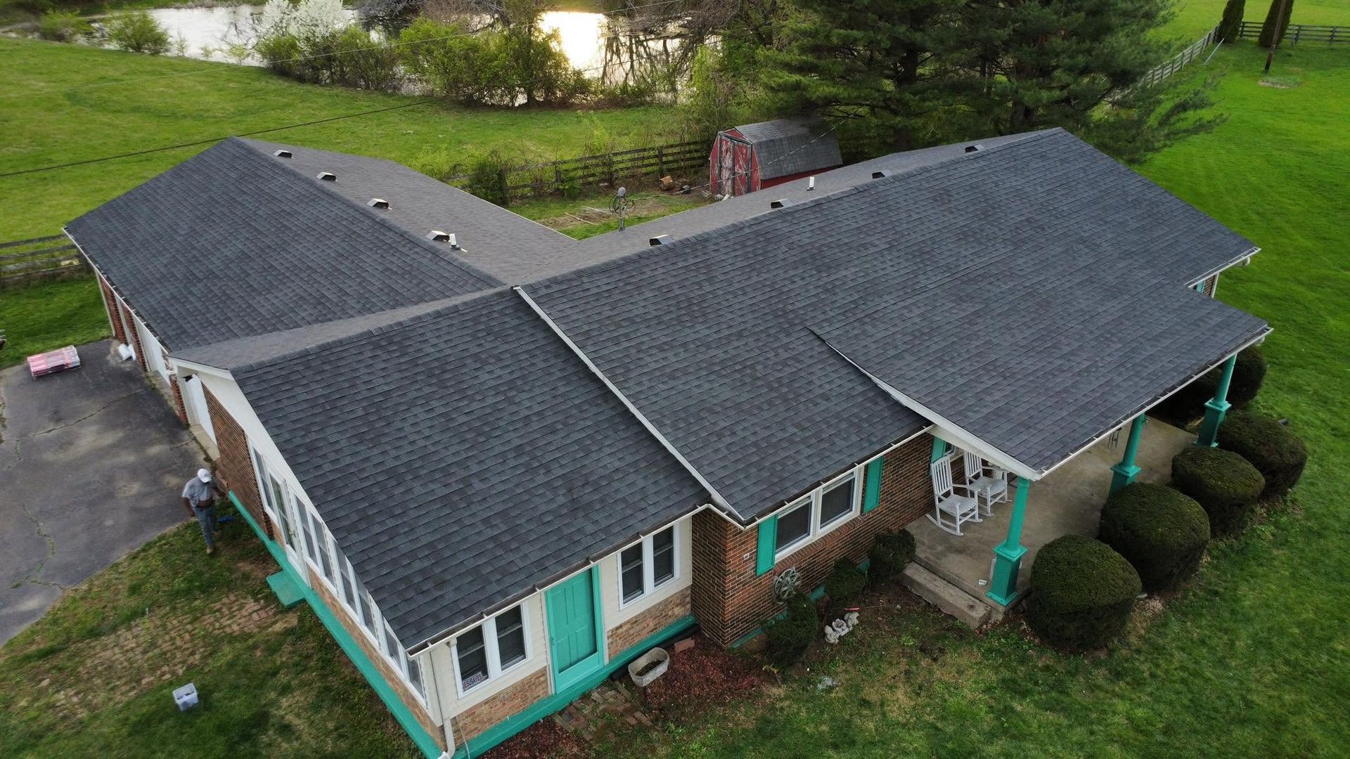 Aerial view of a gray-roofed suburban house with teal trim and a green yard