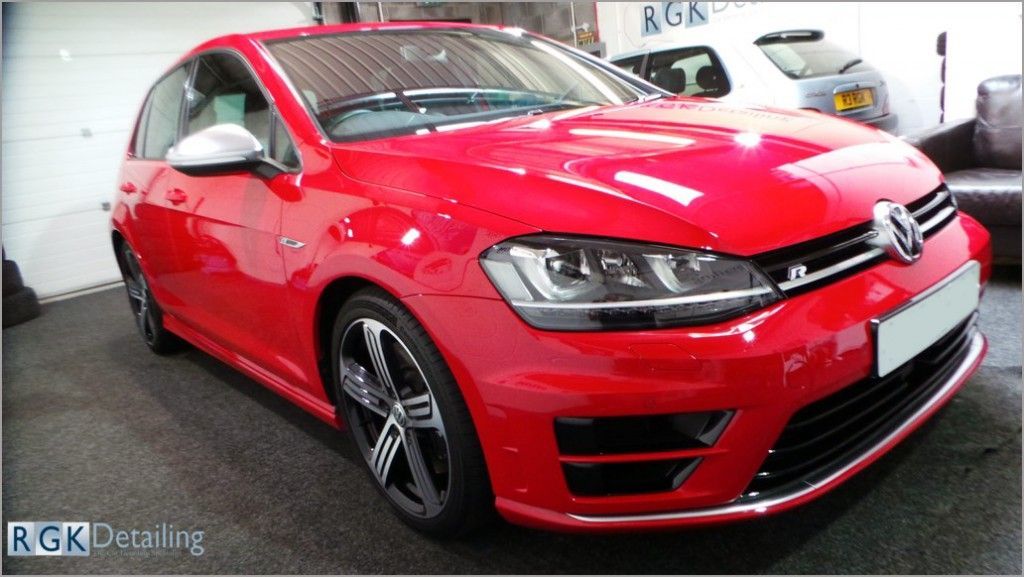 A red volkswagen golf is parked in a garage