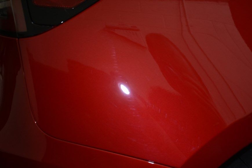 A close up of a red car 's hood in a garage.