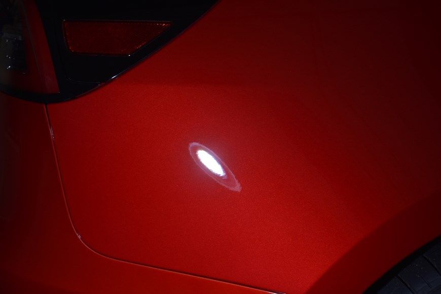 A red car with a white light on the side of it.