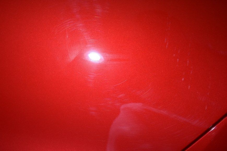 A close up of a red car with a light shining on it.