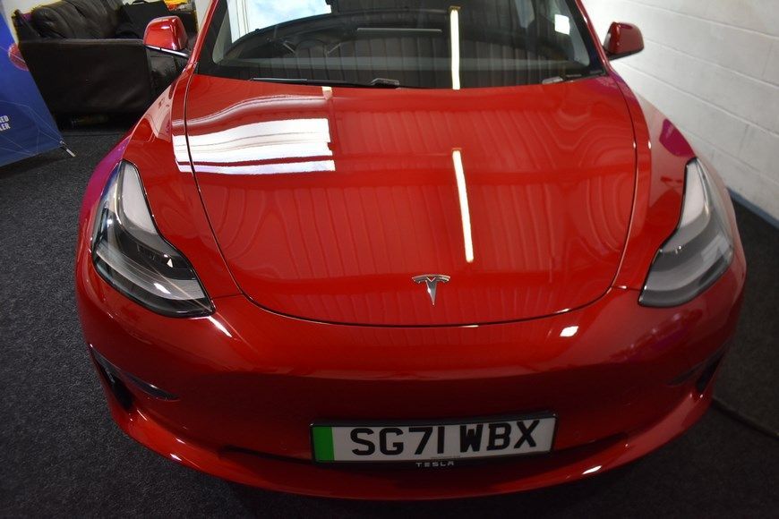 A red tesla model 3 with a license plate that says sg71wbx