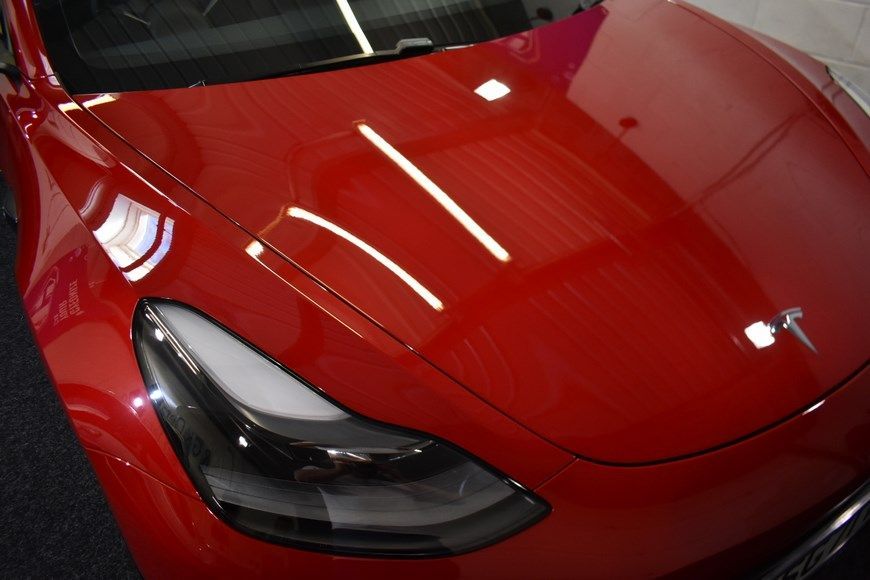 A red tesla model 3 is parked in a garage