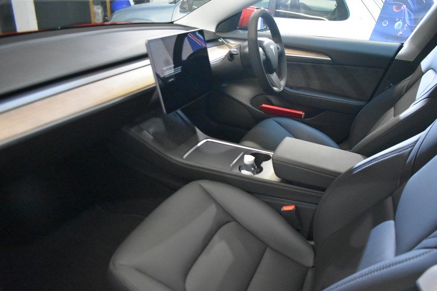 The interior of a tesla model 3 is shown in a showroom.