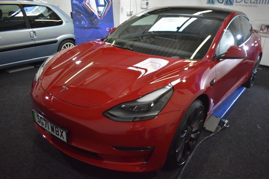 A red tesla model 3 is parked in a showroom