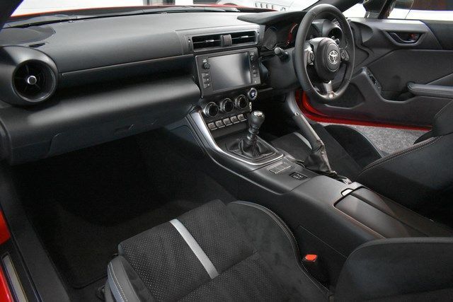 The interior of a red sports car with black seats and a steering wheel.