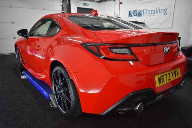 A red sports car is sitting on a lift in a garage.