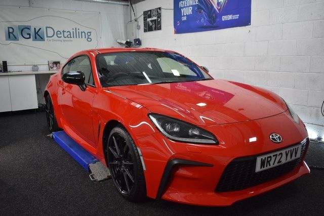 A red sports car is sitting on a lift in a garage.