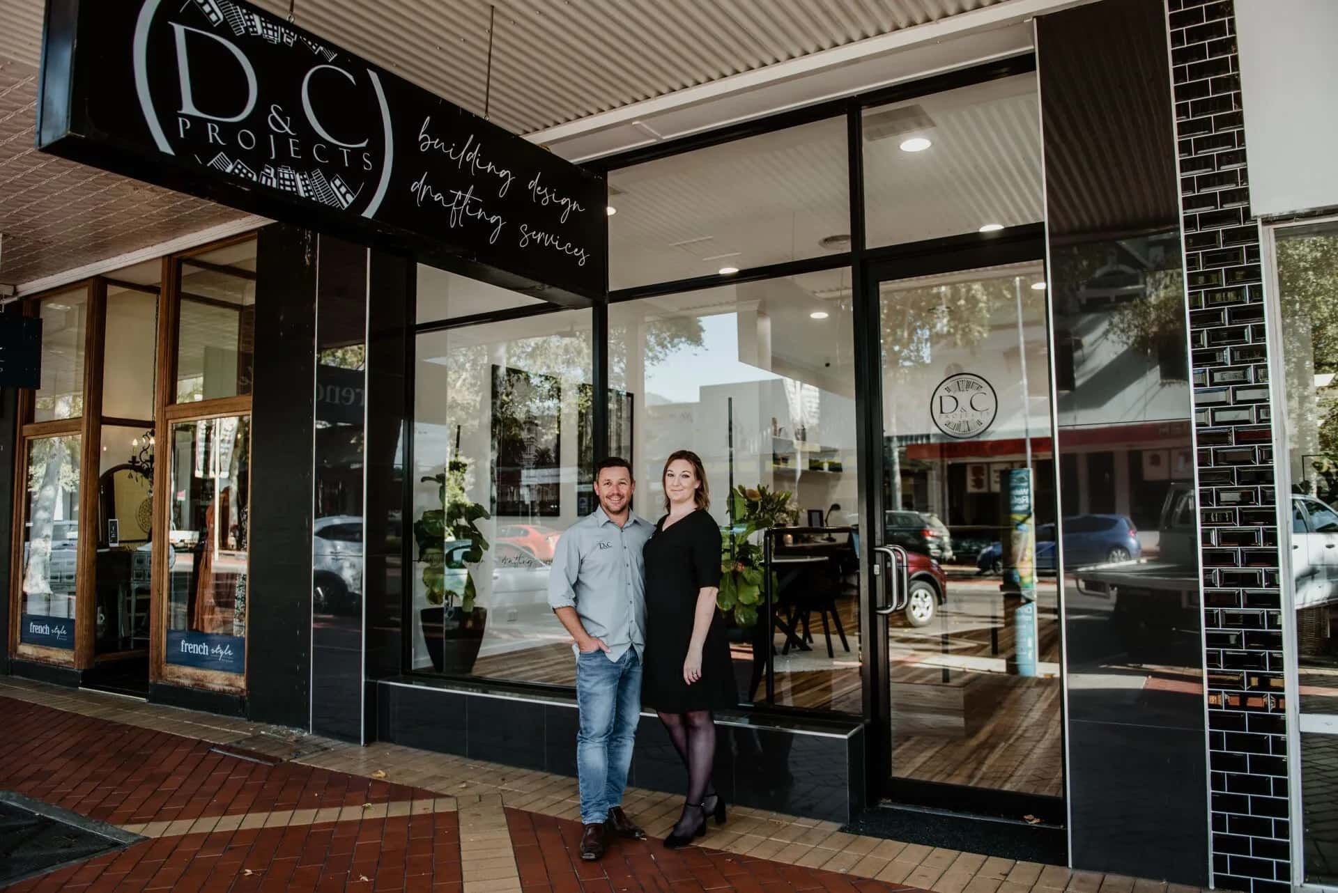Two People Stand Outside a Business With Glass Doors — D&C Projects in Tamworth, NSW