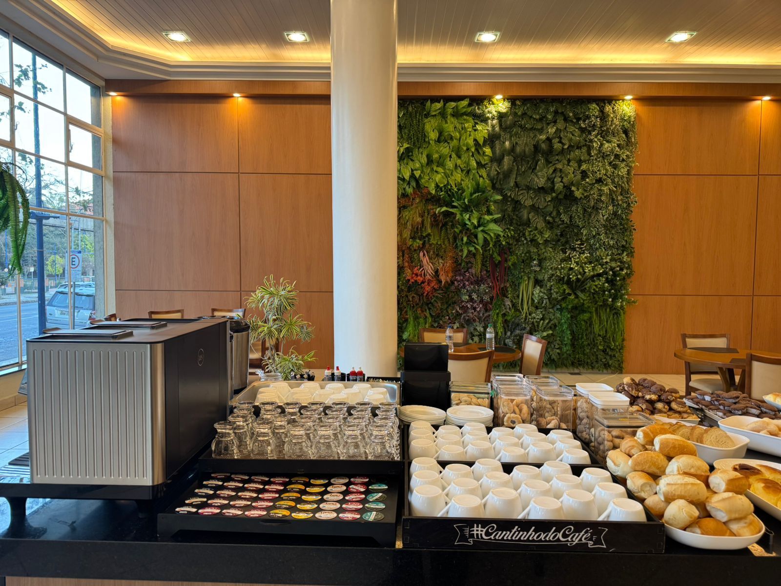 Buffet de café da manhã com doces, muffins e uma parede verde em uma área de jantar bem iluminada.imperador hotel