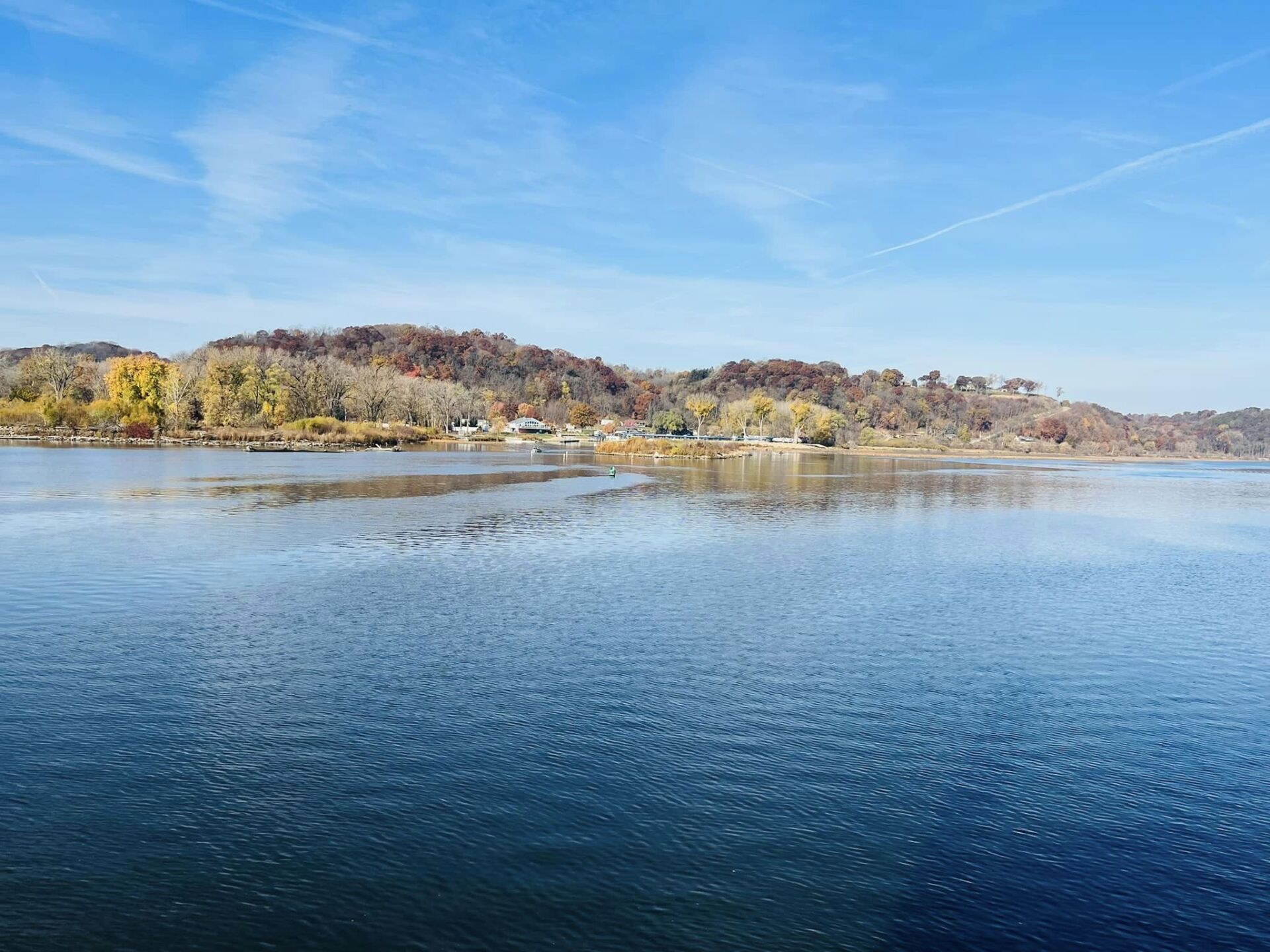 a large body of water surrounded by trees on a sunny day .