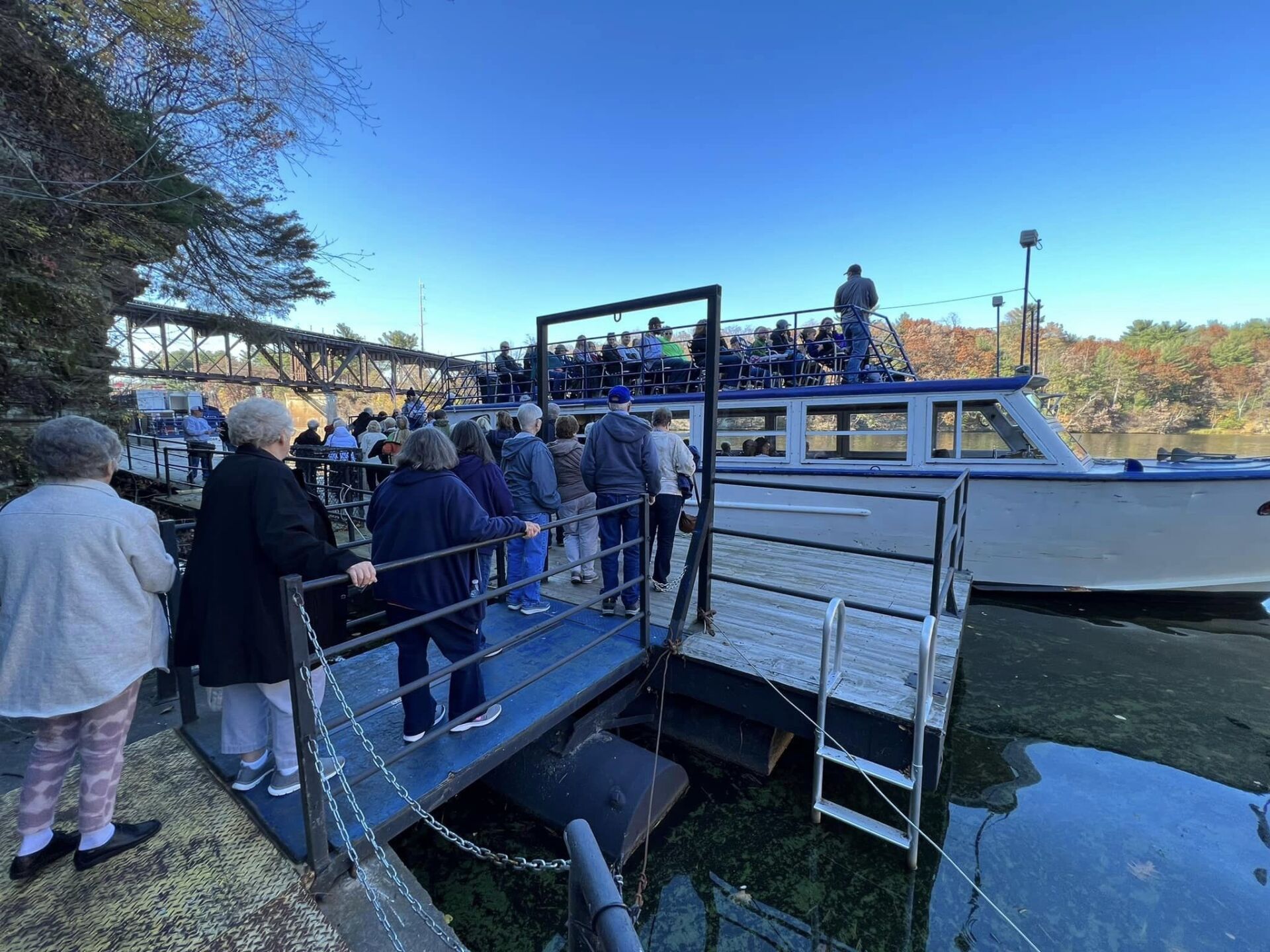 a group of people are standing on a dock next to a boat .