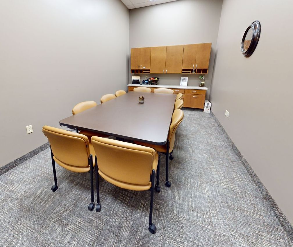 A conference room with a table and chairs and a clock on the wall.