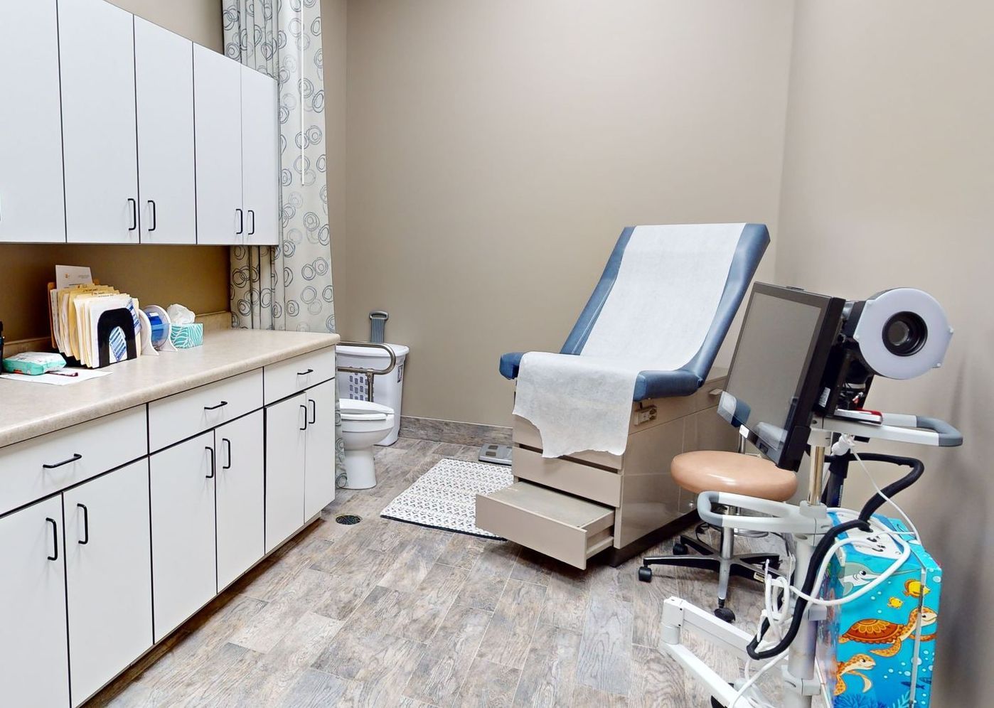 A doctor 's office with a chair and a toilet.