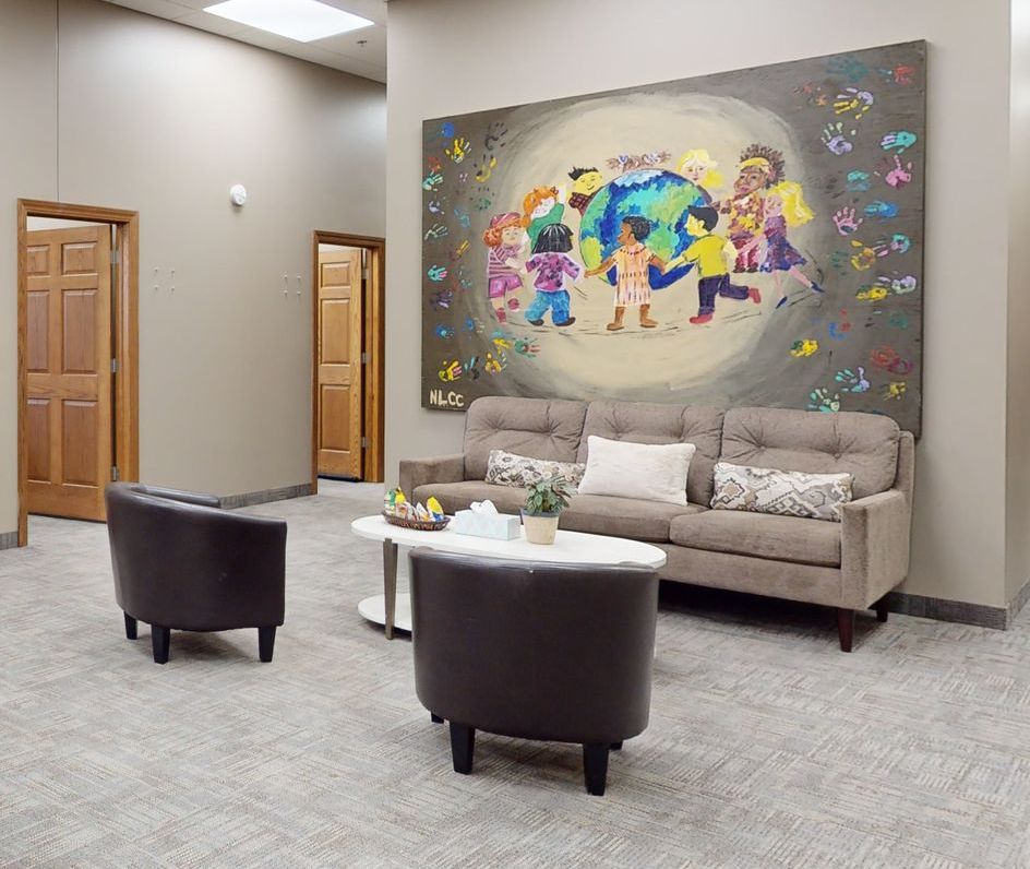 A living room with a couch , chairs , and a painting on the wall.