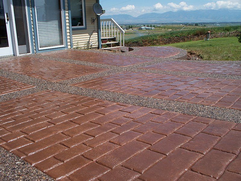 A brick walkway leading to a house with mountains in the background