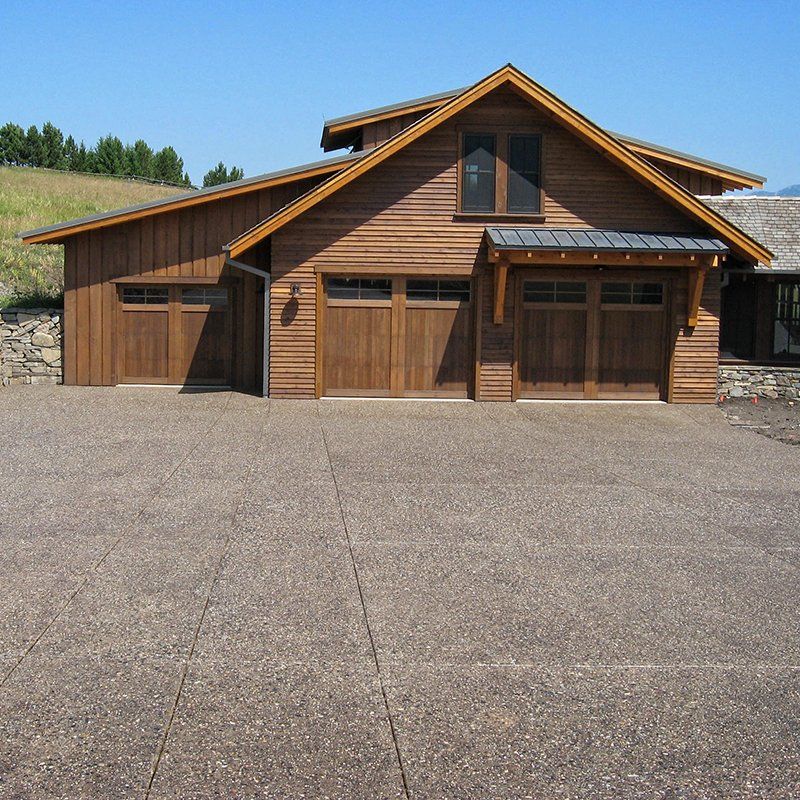 A large wooden house with a driveway in front of it