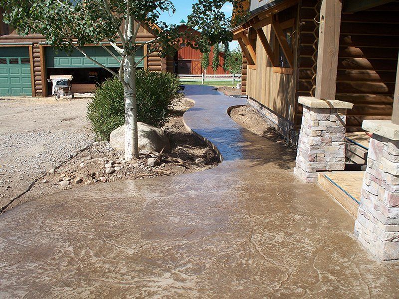 A concrete walkway leading to a log cabin