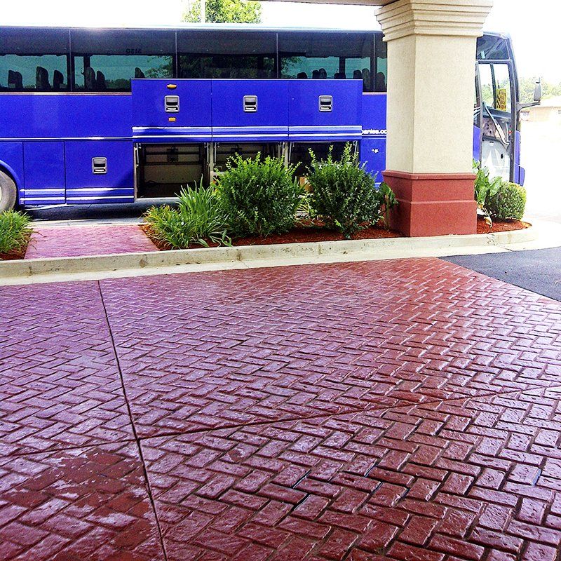 A blue bus is parked in front of a brick driveway