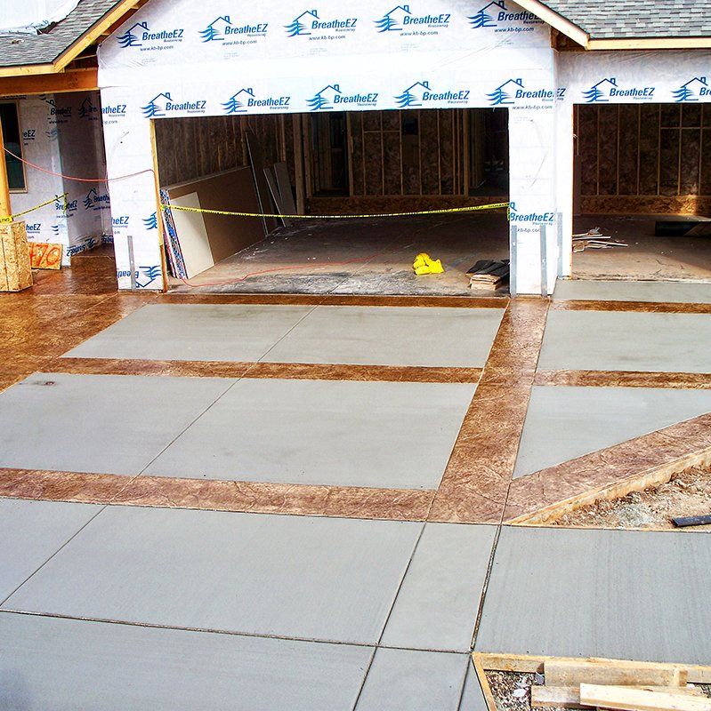 A concrete driveway in front of a house under construction