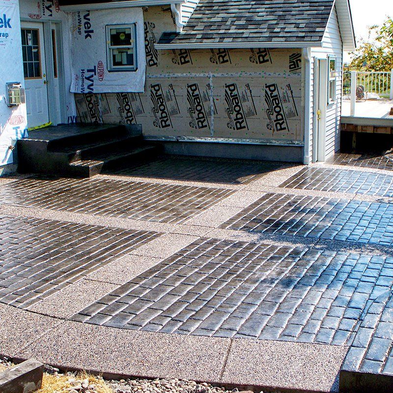 A brick driveway with a house in the background