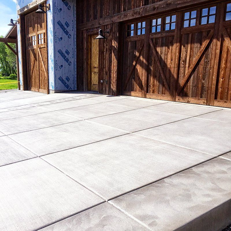 A wooden garage with a concrete driveway in front of it