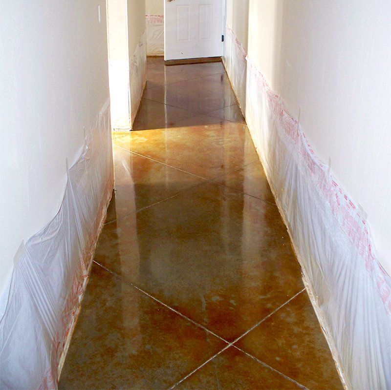 A long hallway with a concrete floor and white walls.