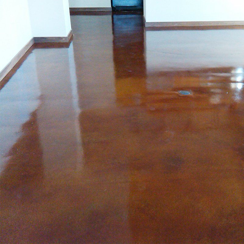 A living room with a brown concrete floor and white walls.