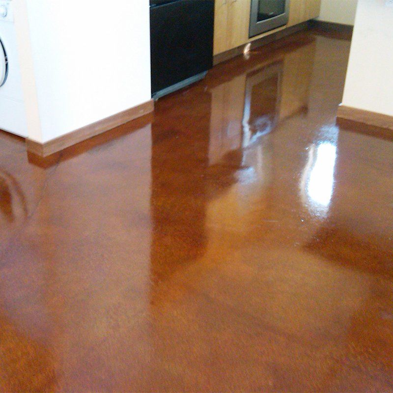 A kitchen with a shiny concrete floor and a washing machine