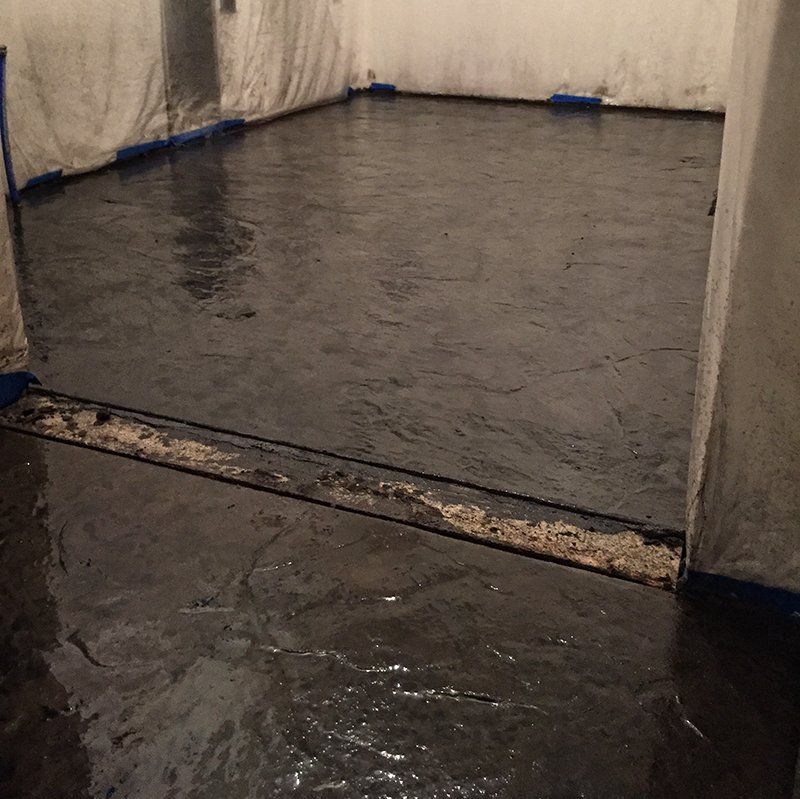 A dark room with a concrete floor that looks like water