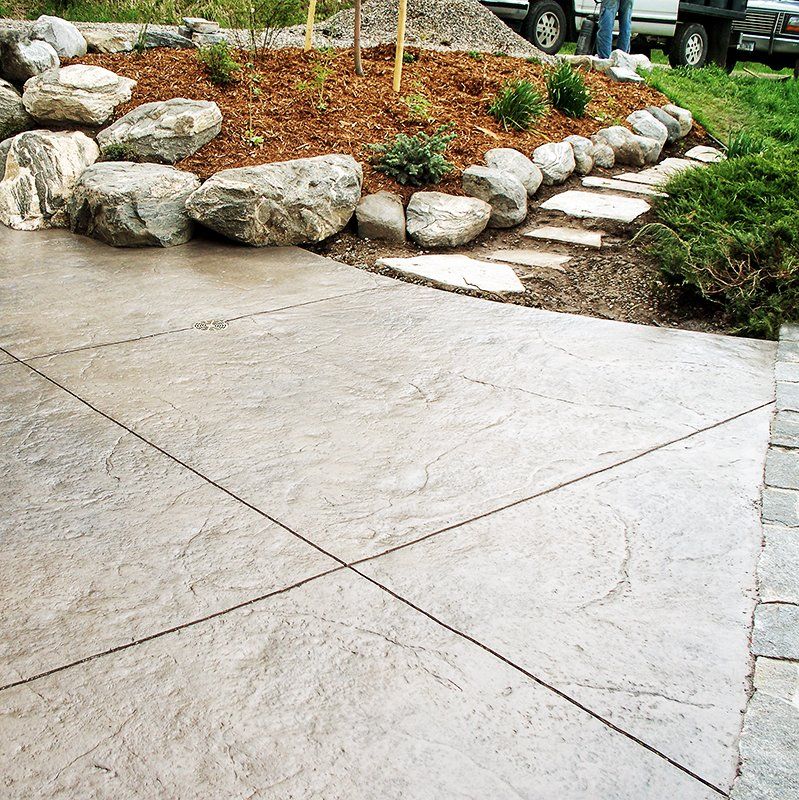A concrete walkway surrounded by rocks and mulch