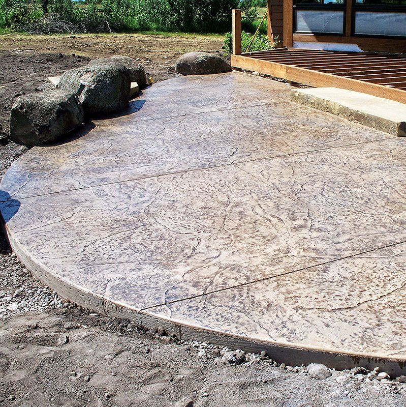 A concrete patio with a wooden deck in the background