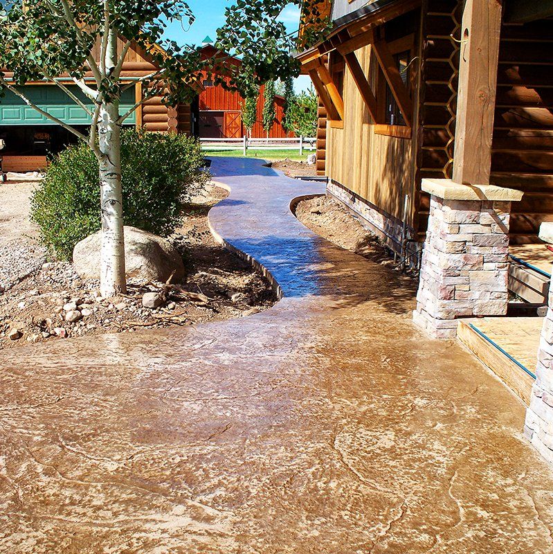 A concrete walkway leading to a log cabin